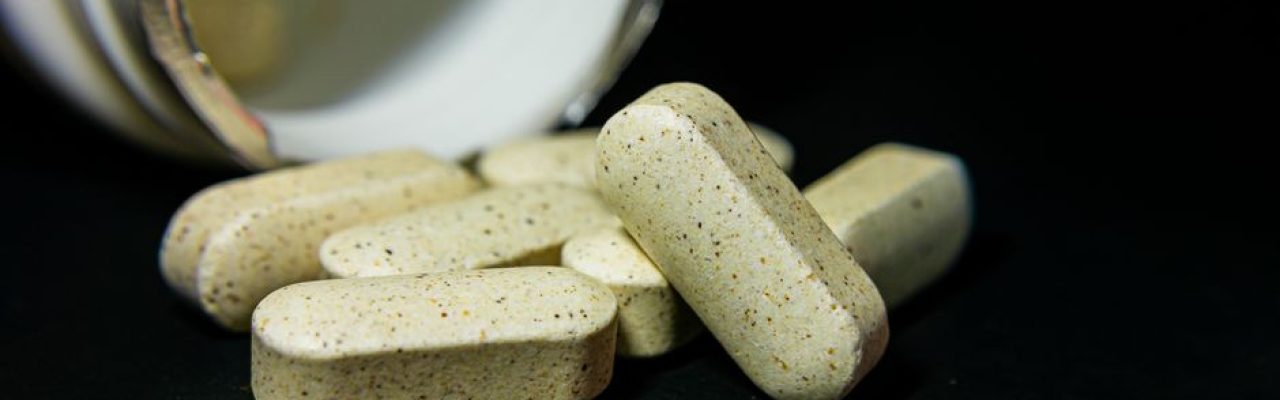 Close-up of white capsule pills spilled from a bottle on a black background. Ideal for health-related visuals.